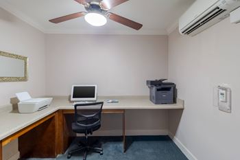 A room with a desk, chair, and a ceiling fan.